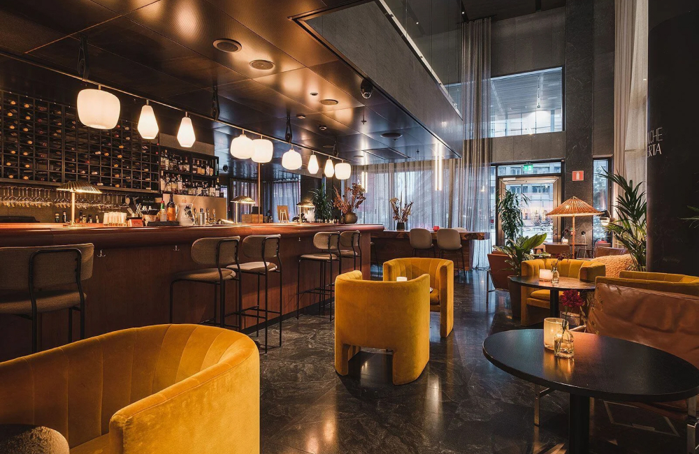 Bar på At Six med gula fåtöljer och bardisk